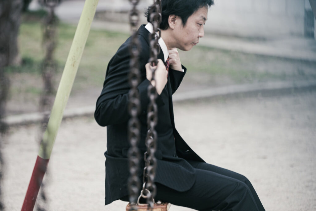 ブランコで黄昏ている男性